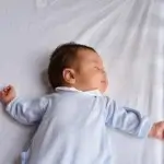 bébé qui dort avec la tête sur le coté